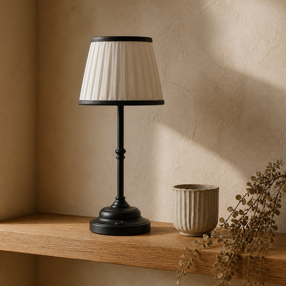 Black Nordic rechargeable table lamp on an oak shelf in soft daylight.